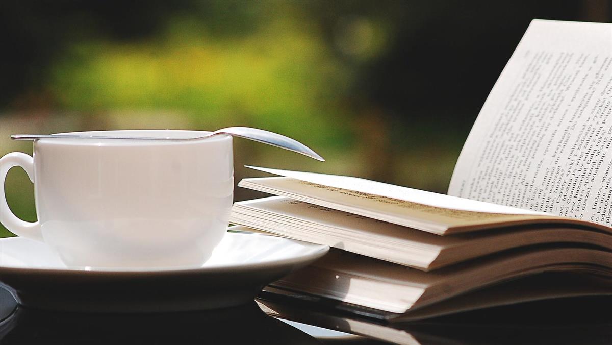 Bord med opplslått bok og ein kopp kaffi. - Klikk for stort bilete