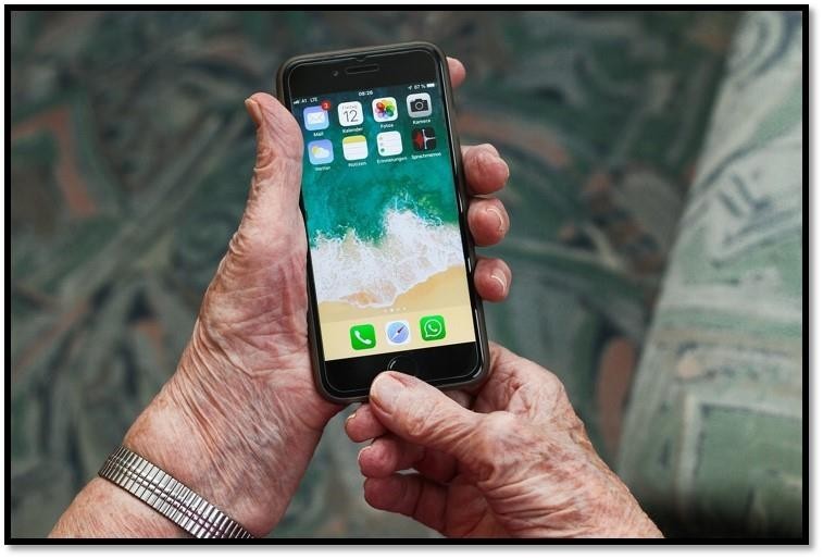 Bilete synar henda til ein eldre person som held ein smarttelefon. 